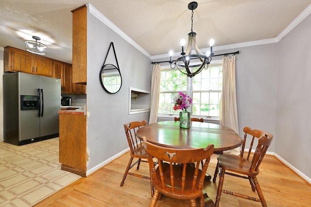 dining area featuring crown molding, baseboards, a notable chandelier, and light wood-style flooring