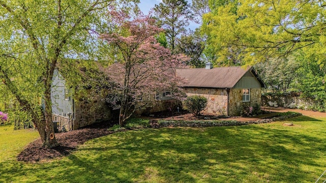 view of side of home with fence, a yard, and stone siding