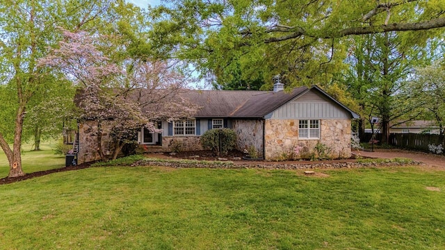 single story home featuring fence, a front yard, and stone siding