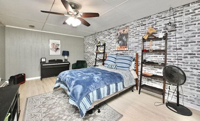 bedroom with brick wall, a ceiling fan, baseboards, wood finished floors, and visible vents