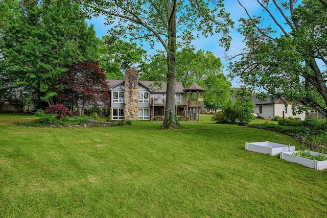 view of yard with a vegetable garden and a balcony