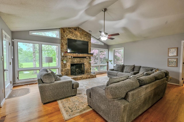 living area featuring a wealth of natural light, wood finished floors, vaulted ceiling, and a fireplace