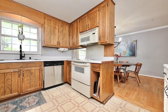 kitchen with crown molding, a sink, white appliances, light countertops, and brown cabinetry
