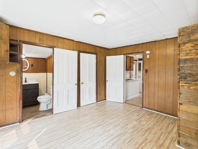 174 E Jackson Ave, Spring City, TN 37381 - unfurnished bedroom featuring wooden walls, ensuite bathroom, light wood-style flooring, and a sink