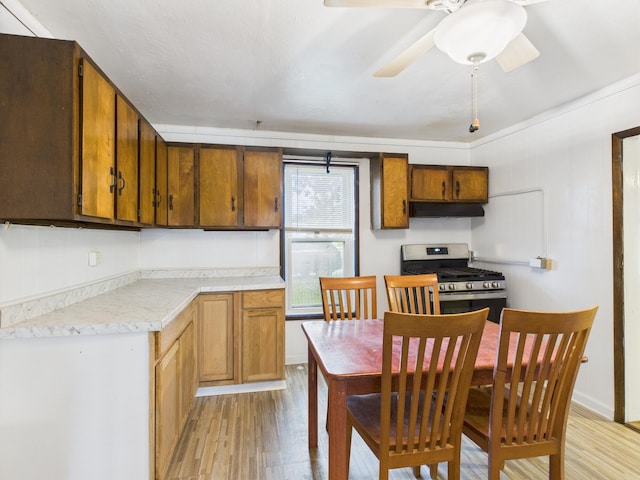 174 E Jackson Ave, Spring City, TN 37381 - kitchen with stainless steel gas stove, under cabinet range hood, light wood-style floors, light countertops, and a ceiling fan