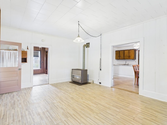 174 E Jackson Ave, Spring City, TN 37381 - unfurnished living room with a wood stove, wood finished floors, a sink, baseboards, and crown molding