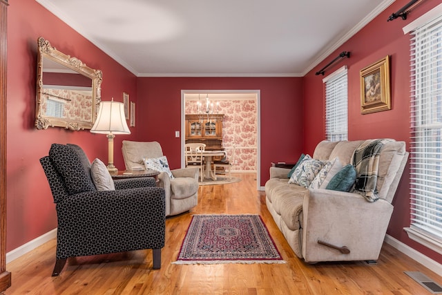 living room with plenty of natural light, an inviting chandelier, ornamental molding, and hardwood / wood-style flooring