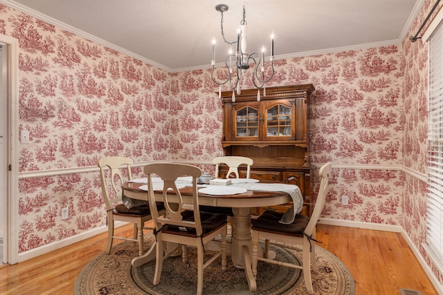 dining room featuring light hardwood / wood-style flooring, ornamental molding, and a notable chandelier