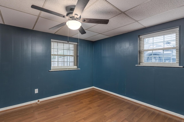 empty room with wood-type flooring, a drop ceiling, and ceiling fan