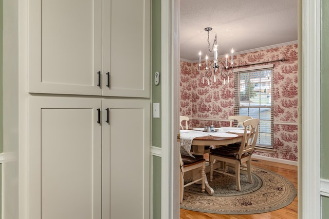 dining space with an inviting chandelier, light wood-type flooring, and ornamental molding