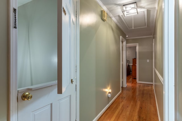 corridor with a textured ceiling, light hardwood / wood-style flooring, and crown molding