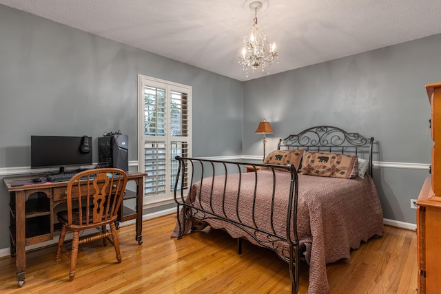 bedroom with a textured ceiling, light hardwood / wood-style floors, and a notable chandelier