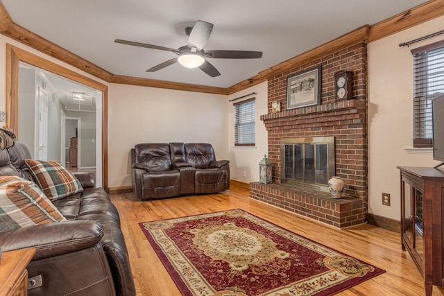 living room with wood-type flooring, a brick fireplace, ceiling fan, and crown molding