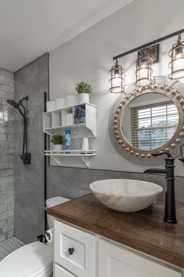 bathroom with a tile shower, vanity, and toilet