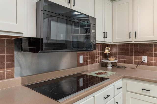 kitchen with black appliances, white cabinetry, and tasteful backsplash