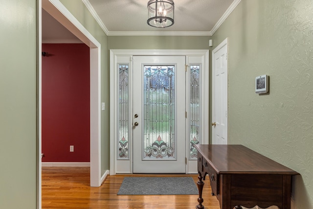 foyer with a textured ceiling, hardwood / wood-style flooring, ornamental molding, and a notable chandelier