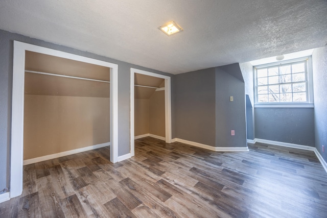 unfurnished bedroom featuring hardwood / wood-style floors, a textured ceiling, and vaulted ceiling