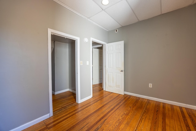 unfurnished bedroom with a paneled ceiling and hardwood / wood-style flooring