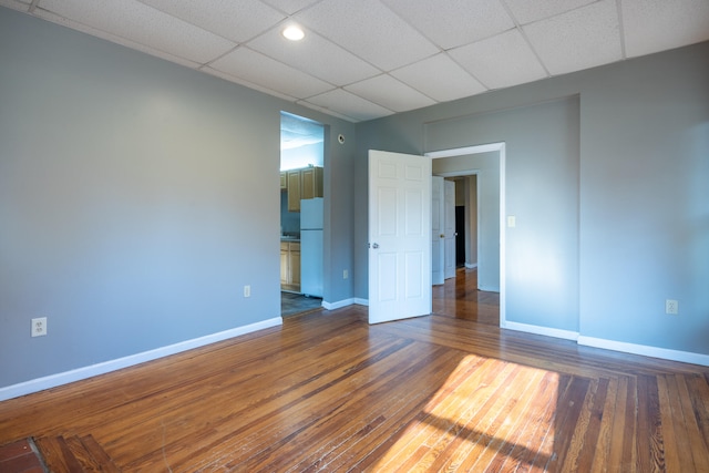 empty room with a paneled ceiling and dark wood-type flooring