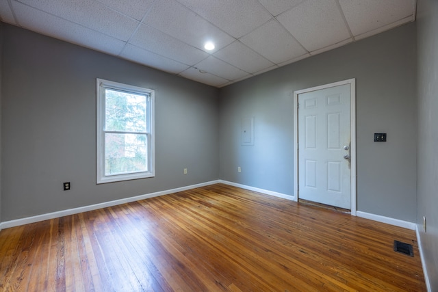 empty room featuring a drop ceiling and wood-type flooring