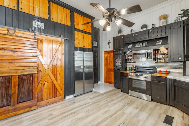 kitchen with a barn door, light hardwood / wood-style floors, stainless steel appliances, and ornamental molding