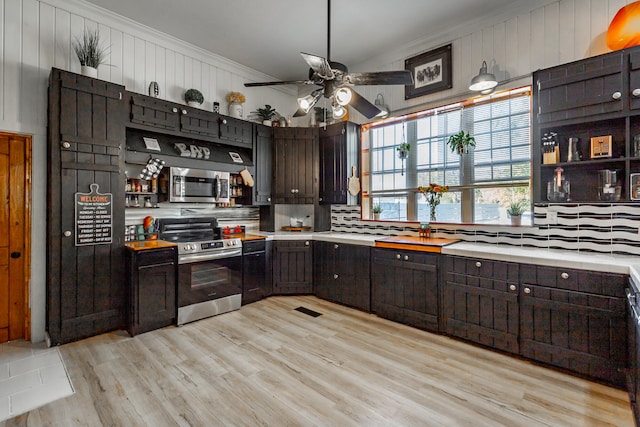 kitchen with appliances with stainless steel finishes, dark brown cabinetry, light hardwood / wood-style flooring, and crown molding