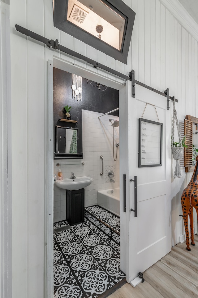 bathroom with shower / tub combination, sink, tile walls, and hardwood / wood-style floors