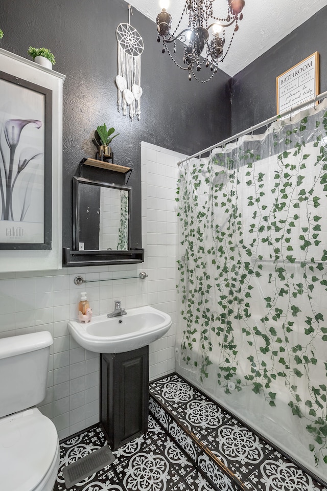 bathroom featuring shower / bath combo, a notable chandelier, tile patterned floors, toilet, and tile walls