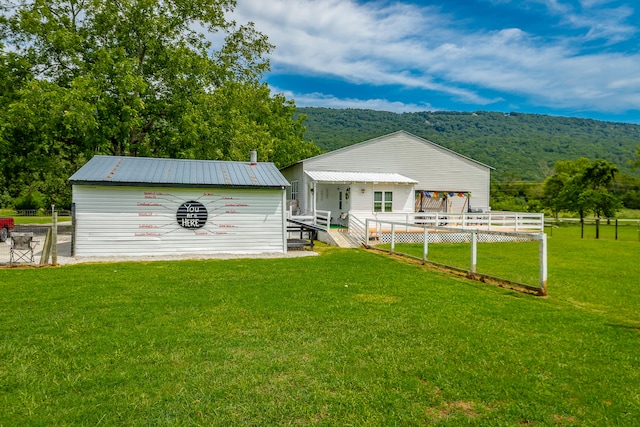 rear view of property featuring a lawn and a deck with mountain view