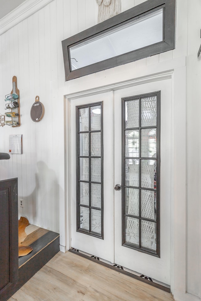 doorway featuring wooden walls and light hardwood / wood-style floors