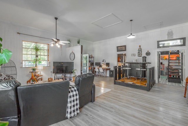 living room featuring bar area, hardwood / wood-style flooring, ceiling fan, and ornamental molding