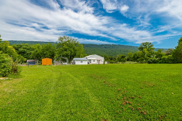 view of yard with a mountain view, a rural view, and an outdoor structure