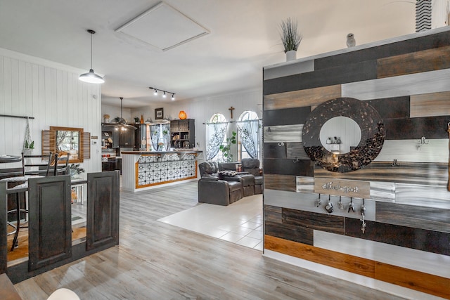 kitchen featuring decorative light fixtures, light hardwood / wood-style floors, and wooden walls