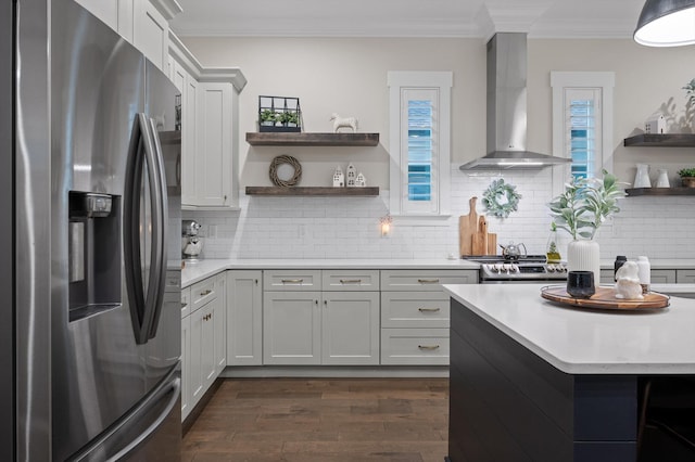 kitchen with crown molding, appliances with stainless steel finishes, open shelves, light countertops, and wall chimney exhaust hood