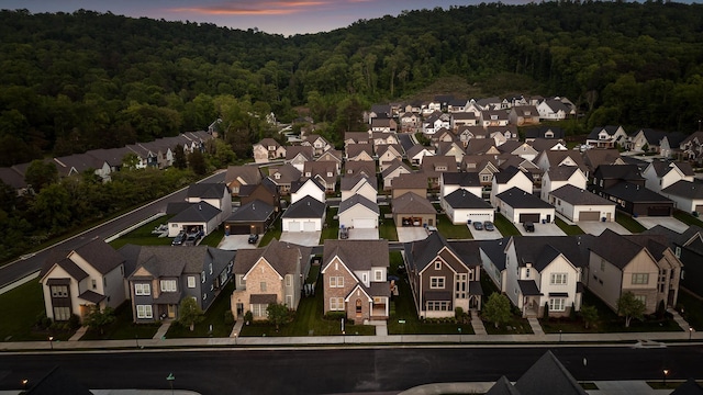 aerial view at dusk featuring a residential view and a view of trees