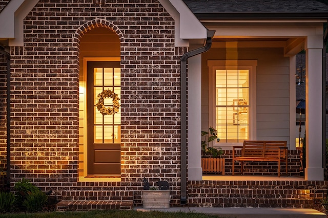 entrance to property with a porch and brick siding