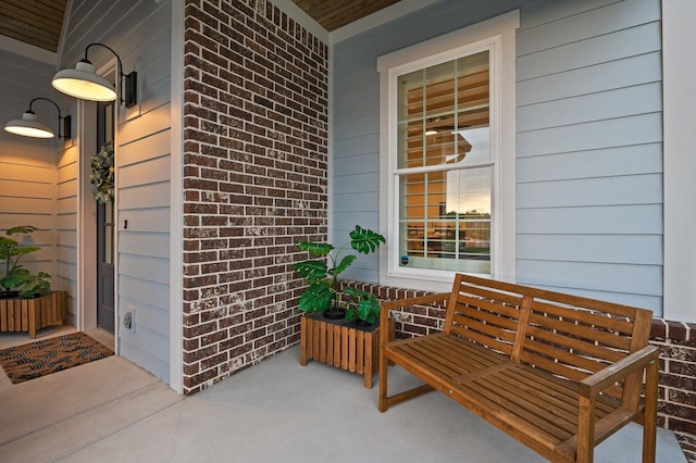view of exterior entry featuring brick siding and a porch