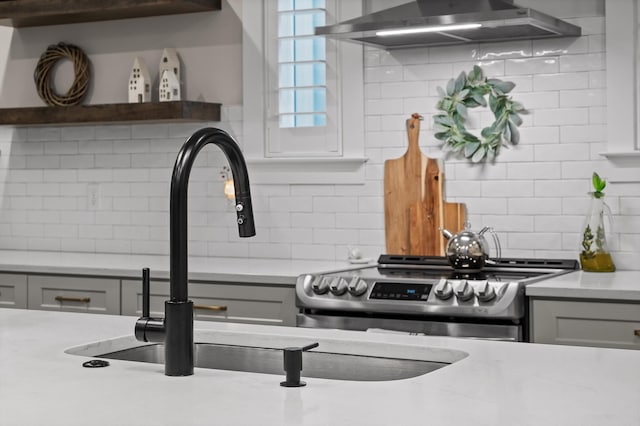 details with light stone countertops, electric stove, decorative backsplash, range hood, and gray cabinetry