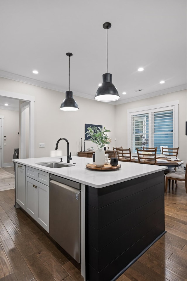 kitchen featuring a kitchen island with sink, stainless steel dishwasher, a sink, light countertops, and dark wood-type flooring