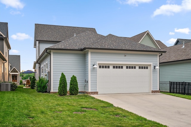 view of front of house with driveway, roof with shingles, a front yard, fence, and an attached garage