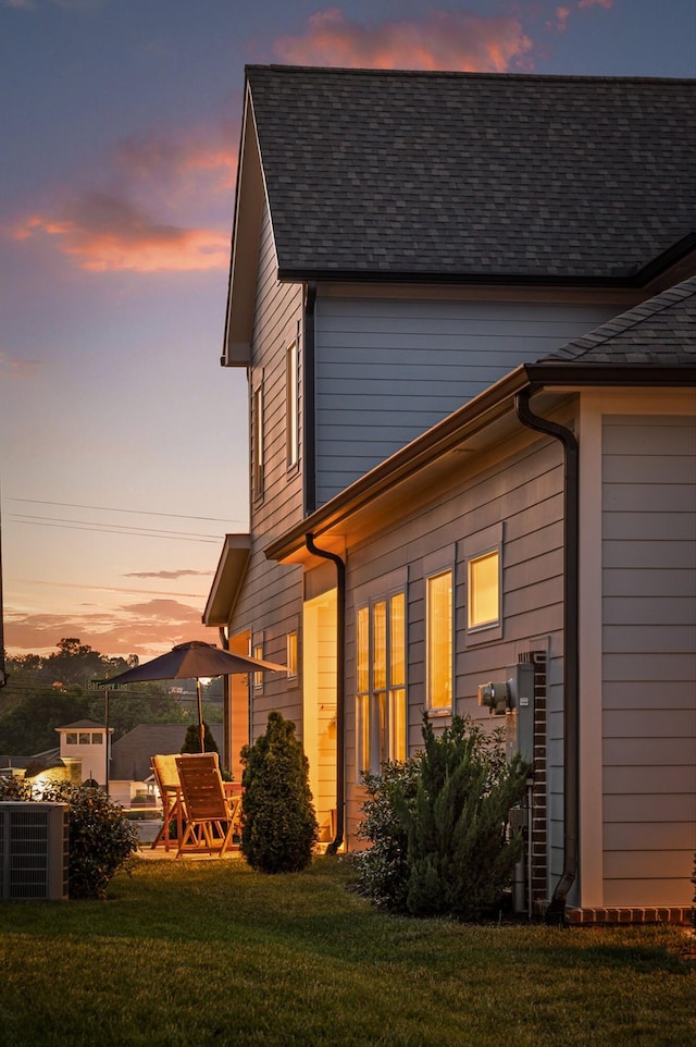property exterior at dusk featuring a lawn and a patio area