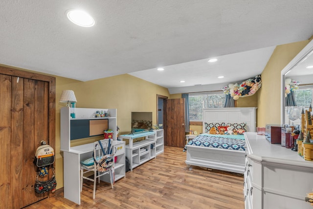 bedroom featuring a textured ceiling, light wood-type flooring, and multiple windows