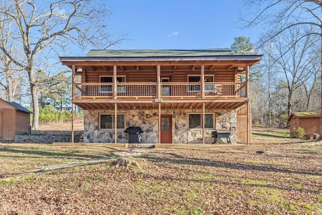 rear view of property featuring a balcony and a storage shed