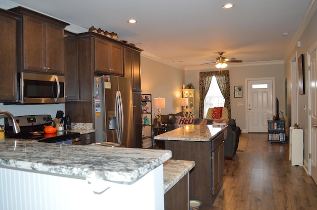 kitchen with appliances with stainless steel finishes, light stone counters, dark brown cabinetry, ceiling fan, and dark wood-type flooring