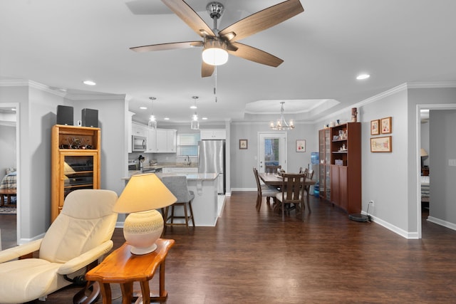 living room featuring ceiling fan with notable chandelier, recessed lighting, dark wood-type flooring, and ornamental molding