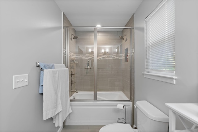 bathroom with shower / bath combination with glass door and toilet