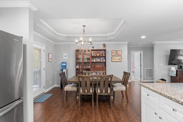 dining area with dark wood finished floors, an inviting chandelier, ornamental molding, and visible vents
