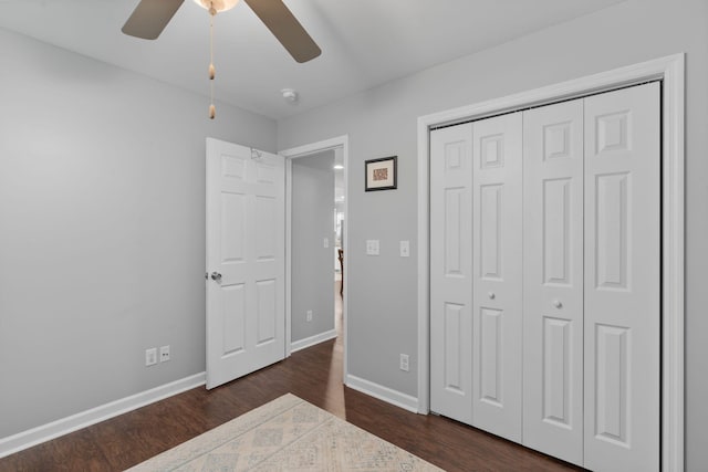 unfurnished bedroom featuring a closet, baseboards, ceiling fan, and dark wood-style floors