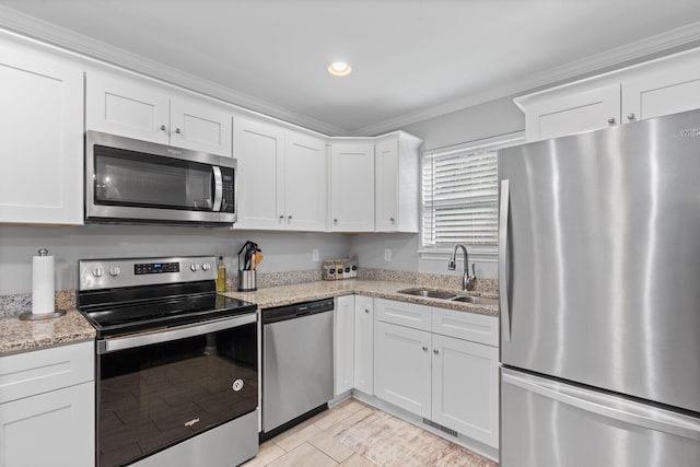 kitchen featuring a sink, white cabinetry, light stone counters, crown molding, and appliances with stainless steel finishes