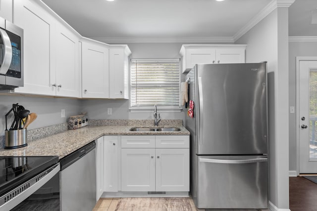 kitchen with white cabinets, light stone counters, ornamental molding, a sink, and appliances with stainless steel finishes